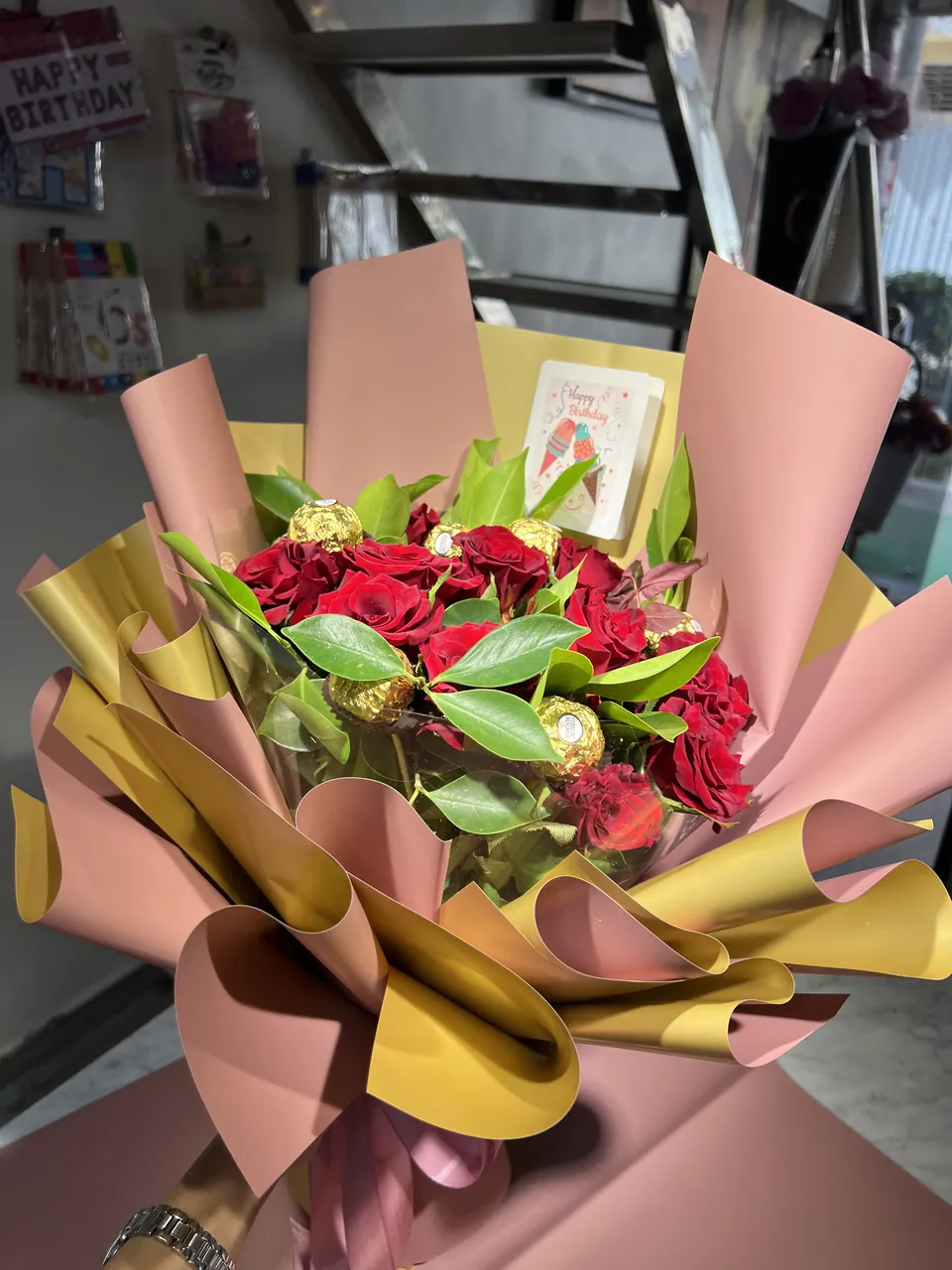 Passion Gourmande – Bouquet roses & chocolat, vue rapprochée, fleurs rouges fraîches, feuillage vert et chocolats dorés